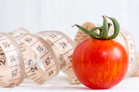 Healthy lifestyle concept with measuring tape and red tomatoの写真素材
