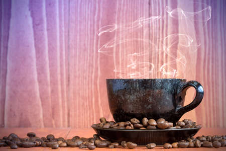 Small cup of black coffee on a wooden background with coffee beans