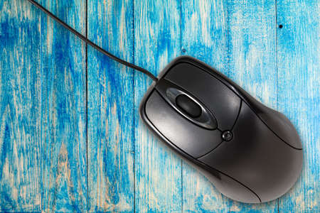 Black computer mouse on the blue wooden planks backgroundの写真素材