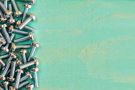 Pile of screw-nuts on the blue wooden background with copy-spaceの写真素材