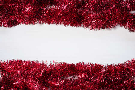 Christmas frame from red tinsel on white wooden backgroundの写真素材