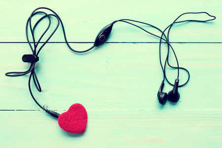 Concept for love music. Earphones connected to the heart. Image toned with retro filter.の写真素材