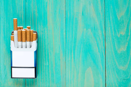 Open pack of cigarettes on blue wooden background with copy-spaceの写真素材