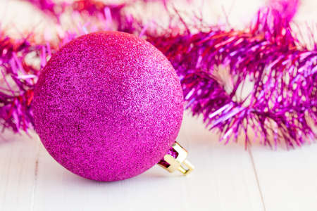 Purple bauble and tinsel on white wooden surfaceの写真素材