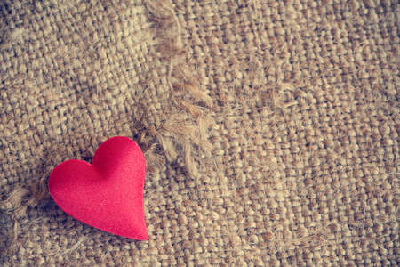 Red heart on gunny sackcloth texture backgroundの写真素材