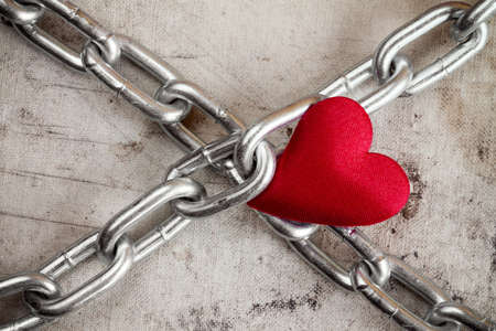 Love. Crossed chains with red heart  on dirty background.の写真素材
