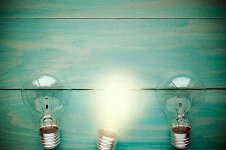 Glow among other lightbulb on a wooden backgroundの写真素材