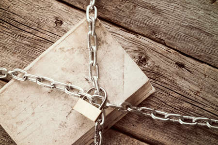 Old book with chain and padlock on wooden background.Vintage style.の写真素材