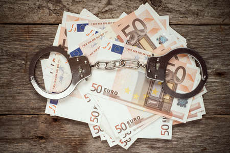 Handcuffs on euro banknotes, corruption or bribery conceptの写真素材