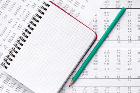 Green pencil and blank notebook on financial chart.Accounting concept.の写真素材