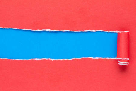Torn red paper on with blue copy-space for textの写真素材