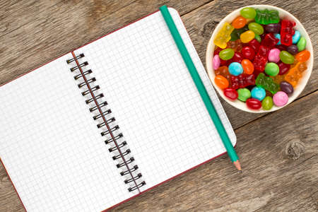 Blank spiral notebook and bowl with mixed candies. Copy-space.の写真素材
