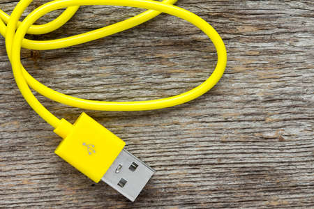Yellow USB cable on wooden background- top viewの写真素材