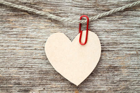 Heart made of paper hanging on wooden background