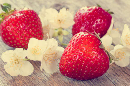Fresh strawberries and white flowers on wooden backgroundの写真素材