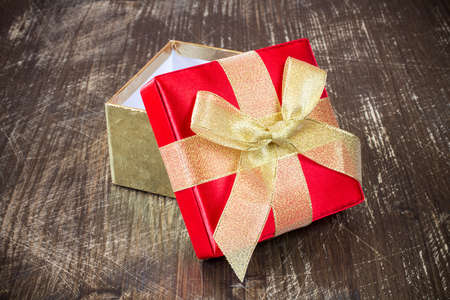 Open gift box with golden ribbon on the old wooden floor