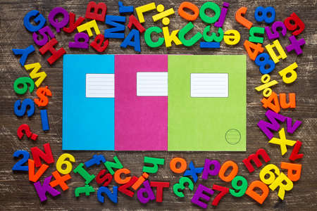 Three exercise books and border of colorful letters and numbersの写真素材