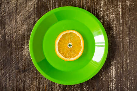 Orange slice in a green plate, top viewの写真素材