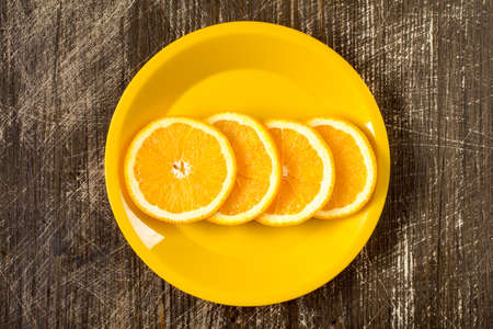 Orange slices in a yellow plate, top viewの写真素材