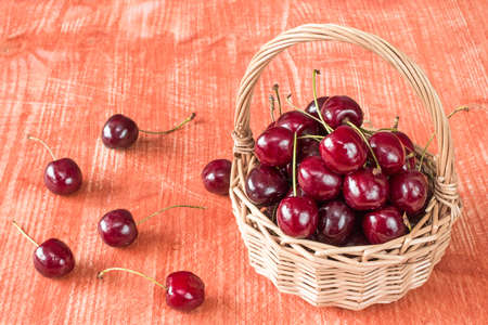 Wicker basket of fresh cherry fruit on the tableの写真素材