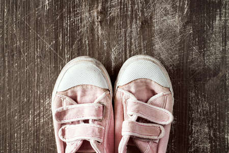 A pair of old pink sneakers on wooden surface.Top view.の写真素材