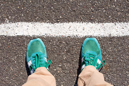Feet are on the road with a white stripeの写真素材