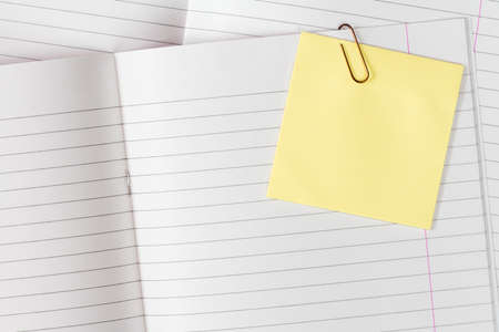 Lined exercise books with blank yellow sticky note