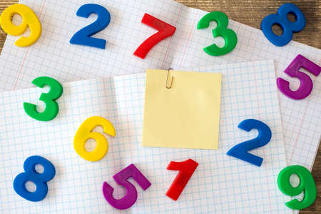 Squared exercise book with colored numbers and blank sticky noteの写真素材