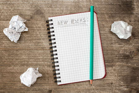 Notebook for new ideas and crumpled paper on the wooden desk