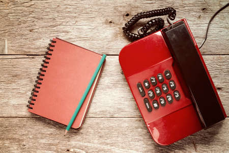 Old telephone and personal organizer with pencil on wooden backgroundの写真素材