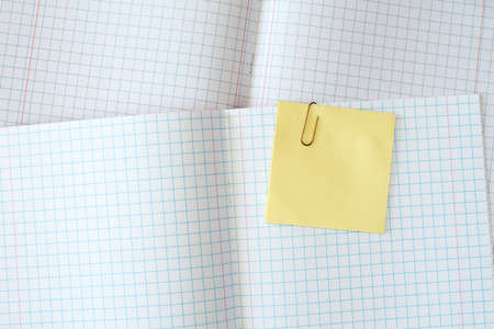 Squared exercise book with blank yellow sticky noteの写真素材