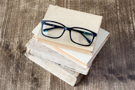 Top view of books and reading glasses on the wooden background.の写真素材