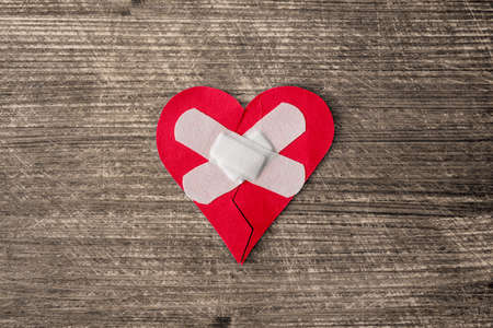 Broken heart with plaster on the old wooden backgroundの写真素材