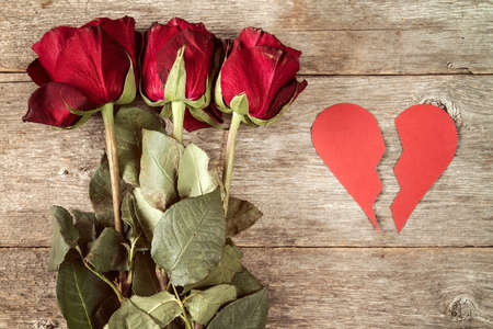 Divorce concept - red broken heart with dry roses on wooden backgroundの写真素材