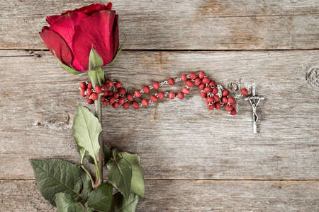 Rosary and old rose on wooden background with copy-space