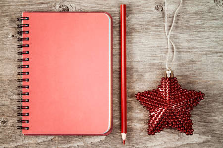 Blank notebook with red pencil and Christmas star on wooden backgroundの写真素材