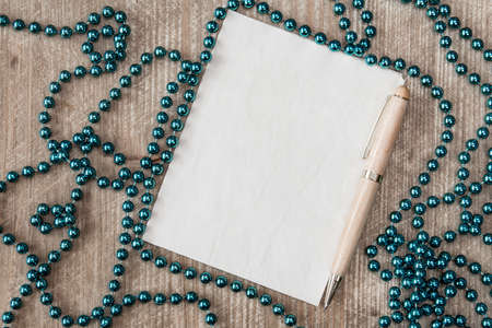 The blank sheet of paper on the wooden table with a pen and Christmas decorationsの写真素材
