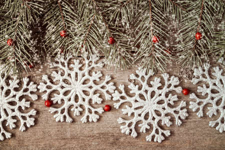 Wooden background with fir branch and silver shiny snowflakesの写真素材