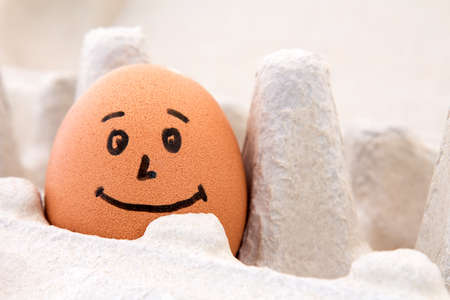 Smiling egg in a carton box, close up viewの写真素材