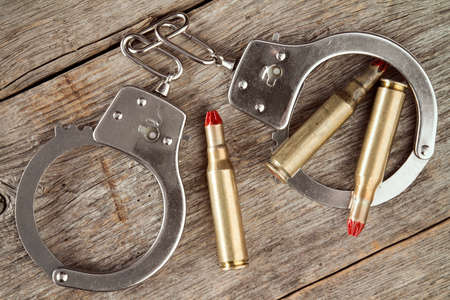 Metal handcuffs and dummy cartridges on the wooden background の写真素材