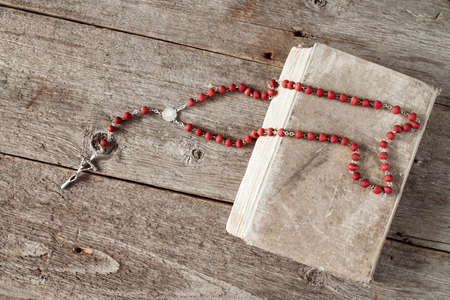 The rosary and old book on wooden background.Top view.