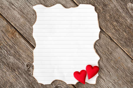 Valentine's day background with burned paper piece and red hearts の写真素材