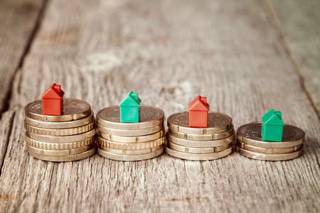 Miniature plastic houses on top of stacked coinsの写真素材