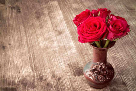 Bouquet of red roses in a vase on wooden backgroundの写真素材