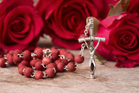 Silver crucifix and red roses on wooden backgroundの写真素材