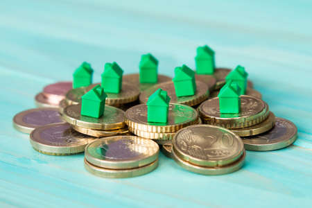 Miniature houses resting on coins pile. Concept for property ladder, mortgage and real estate investmentの写真素材