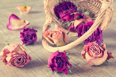 Dried roses flower buds in wicker basket on wooden backgroundの写真素材