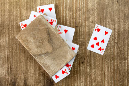 Old book and playing cards on wooden background の写真素材