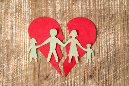 Paper family with broken heart on wooden table , divorce concept