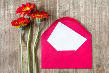 Envelope with blank letter and three gerberas on the wooden tableの写真素材